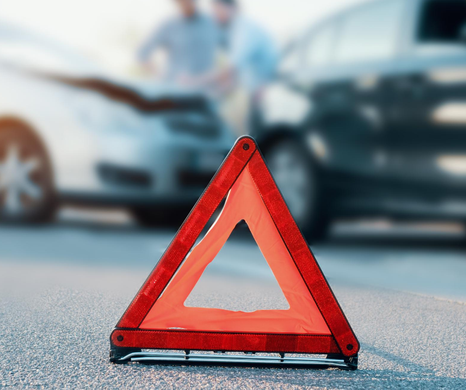 a reflective triangle on the ground in the camera's focus in front of a car accident that is out of focus